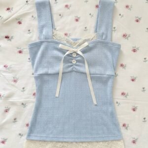 A light blue pointelle knit sleeveless top with cream lace trim on the neckline and hem, featuring a white ribbon bow and small white buttons on the chest, laid on a floral rose-print background